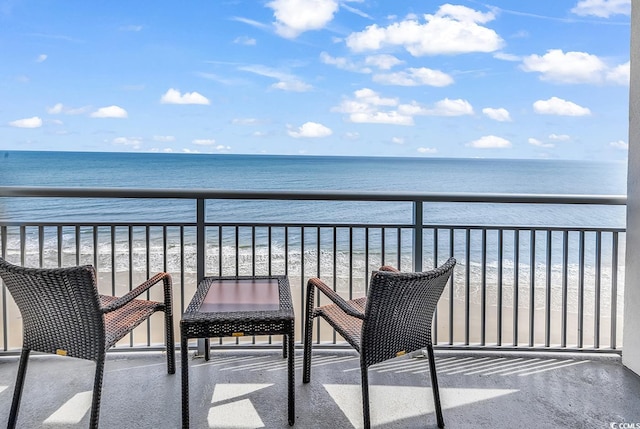 balcony featuring a view of the beach and a water view