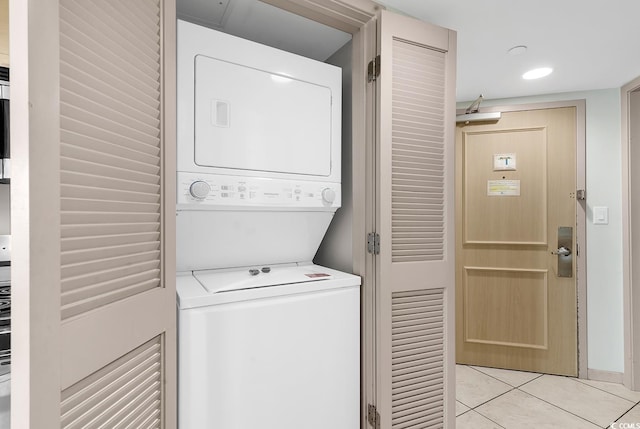 laundry room featuring light tile patterned floors, laundry area, and stacked washing maching and dryer