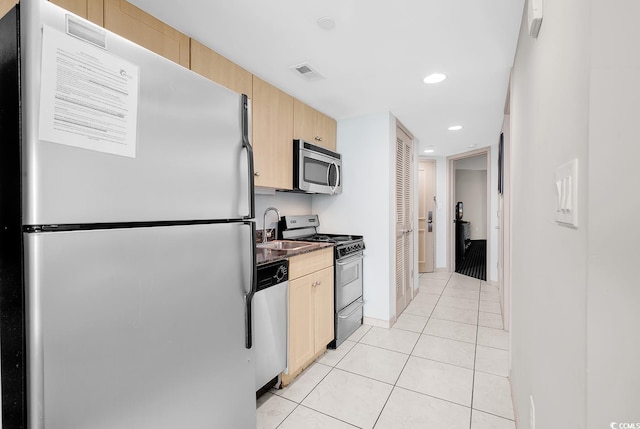 kitchen featuring light tile patterned floors, visible vents, appliances with stainless steel finishes, light brown cabinets, and a sink