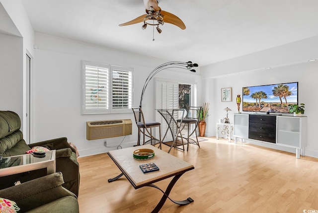 living area with baseboards, a ceiling fan, an AC wall unit, and wood finished floors