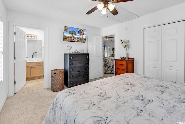 bedroom with light carpet, a closet, a ceiling fan, ensuite bathroom, and a sink