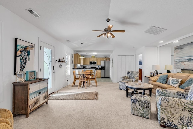 living room with light carpet, ceiling fan, visible vents, and vaulted ceiling