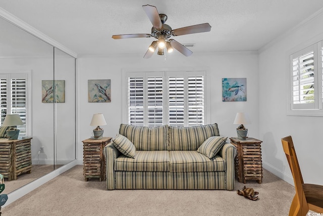 living area with baseboards, carpet floors, a ceiling fan, and crown molding