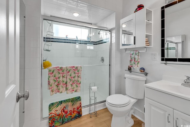 full bathroom with vanity, wood finished floors, a shower stall, and toilet