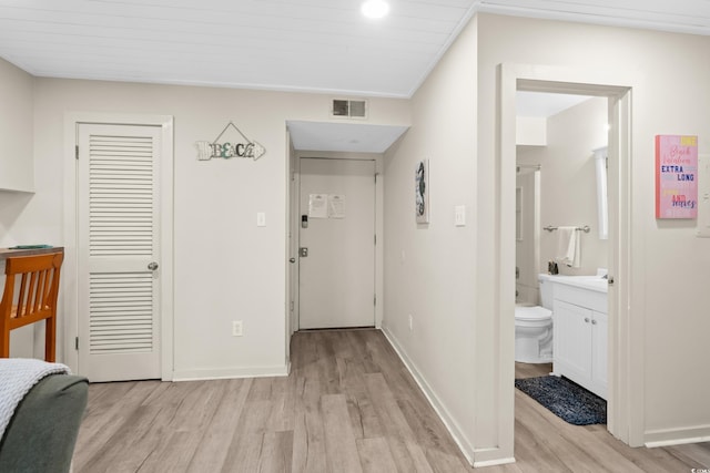 corridor with visible vents, baseboards, and light wood-style floors