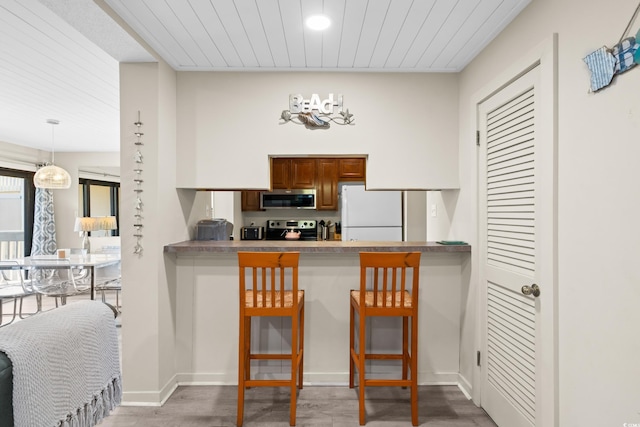 kitchen featuring a kitchen breakfast bar, stainless steel appliances, baseboards, and wood finished floors