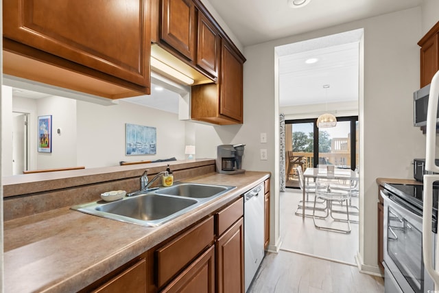 kitchen with a sink, stainless steel appliances, light wood-style floors, brown cabinetry, and light countertops