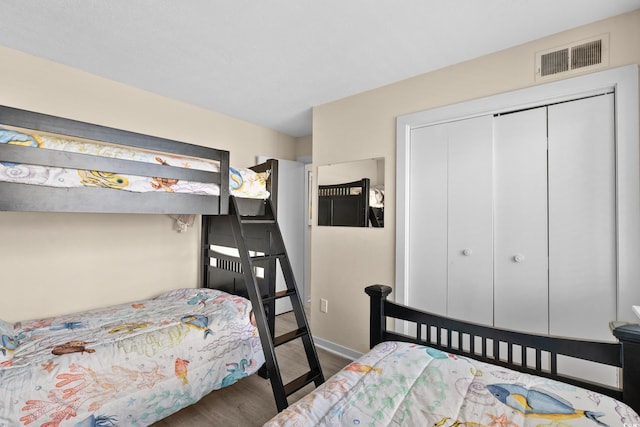 bedroom with visible vents, a closet, and wood finished floors