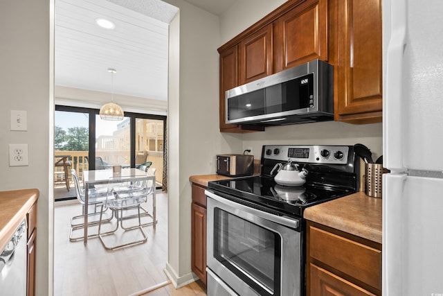 kitchen featuring brown cabinetry, pendant lighting, stainless steel appliances, and light countertops