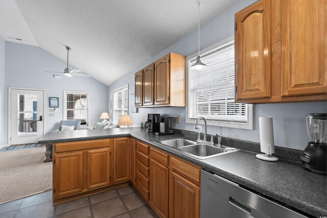 kitchen featuring dark countertops, stainless steel dishwasher, open floor plan, a sink, and a peninsula