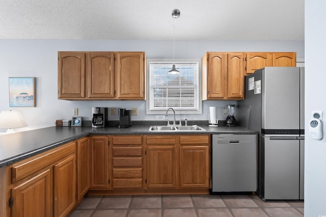 kitchen featuring stainless steel appliances, dark countertops, a sink, and brown cabinets