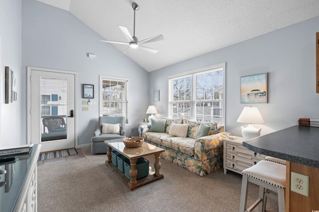 carpeted living room with a textured ceiling, high vaulted ceiling, and a ceiling fan