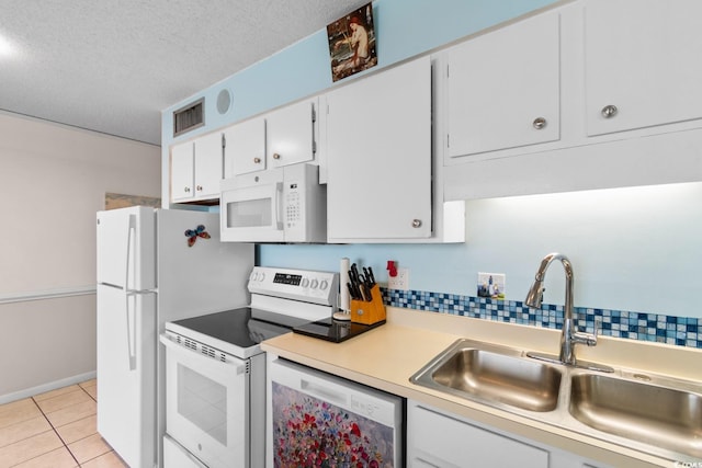 kitchen featuring a textured ceiling, light tile patterned floors, white appliances, a sink, and visible vents