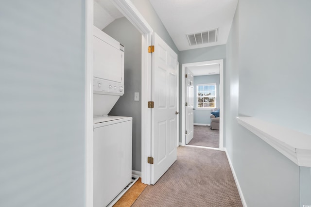 interior space with light colored carpet, stacked washer and clothes dryer, visible vents, and baseboards