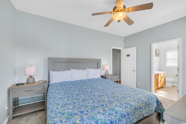 bedroom featuring ceiling fan, baseboards, light colored carpet, and ensuite bathroom