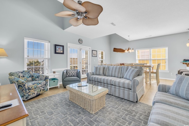 tiled living room with a healthy amount of sunlight, visible vents, baseboards, and ceiling fan with notable chandelier