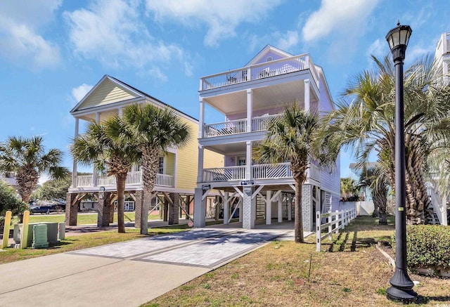 coastal home with a balcony, decorative driveway, and a carport