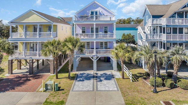 beach home featuring decorative driveway, a carport, and a front yard