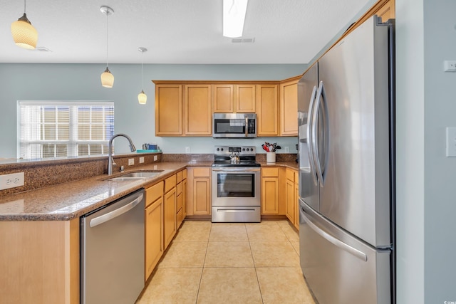 kitchen featuring light tile patterned flooring, stainless steel appliances, a peninsula, a sink, and decorative light fixtures