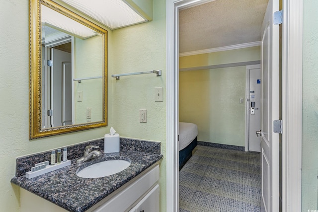 bathroom with a textured ceiling, vanity, crown molding, and a textured wall