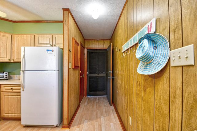 kitchen with wood walls, light wood-style flooring, a textured ceiling, and freestanding refrigerator