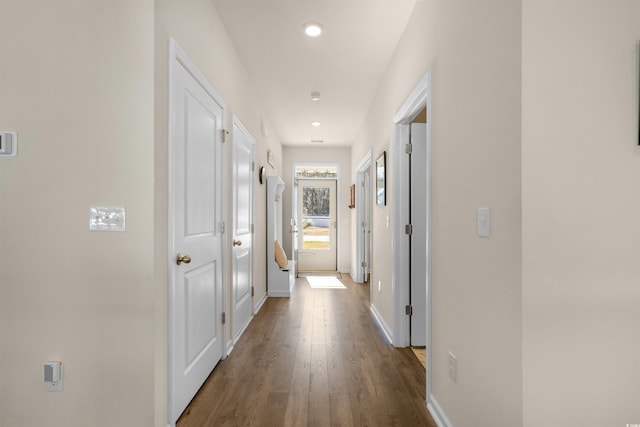 corridor with dark wood-style floors, baseboards, and recessed lighting