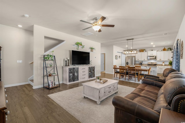 living area with ceiling fan, visible vents, baseboards, stairway, and dark wood-style floors