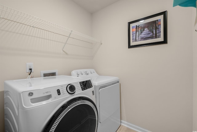 washroom featuring laundry area, baseboards, and washer and clothes dryer