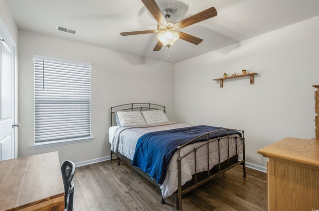 bedroom with ceiling fan, wood finished floors, visible vents, and baseboards