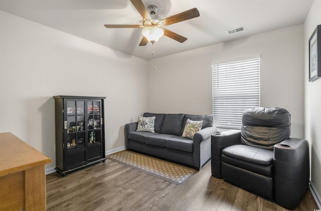 living room featuring a ceiling fan, wood finished floors, visible vents, and baseboards