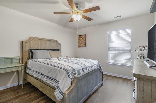 bedroom featuring a ceiling fan, visible vents, baseboards, and wood finished floors