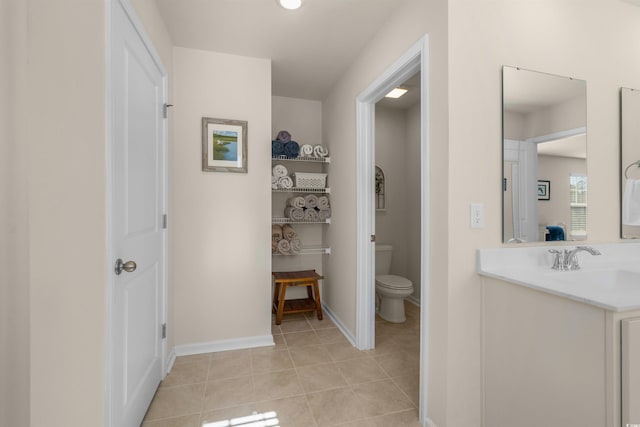 bathroom featuring toilet, vanity, baseboards, and tile patterned floors