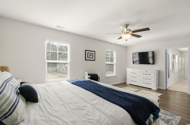 bedroom with visible vents, ceiling fan, ensuite bath, wood finished floors, and baseboards