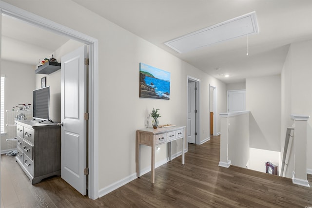 corridor featuring attic access, baseboards, dark wood finished floors, and an upstairs landing