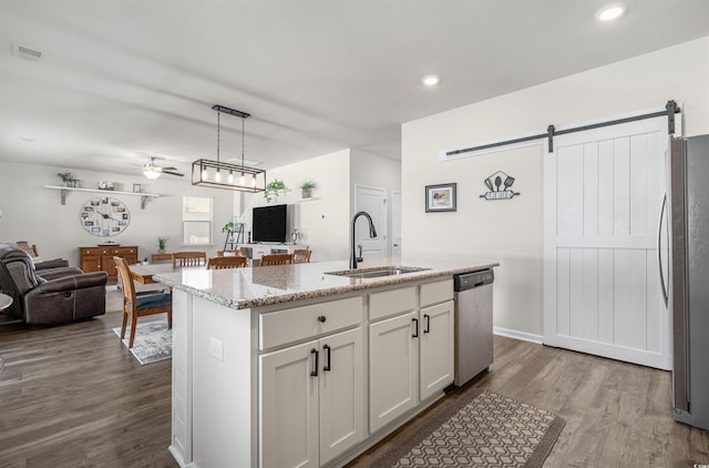 kitchen featuring a barn door, stainless steel appliances, a sink, visible vents, and open floor plan