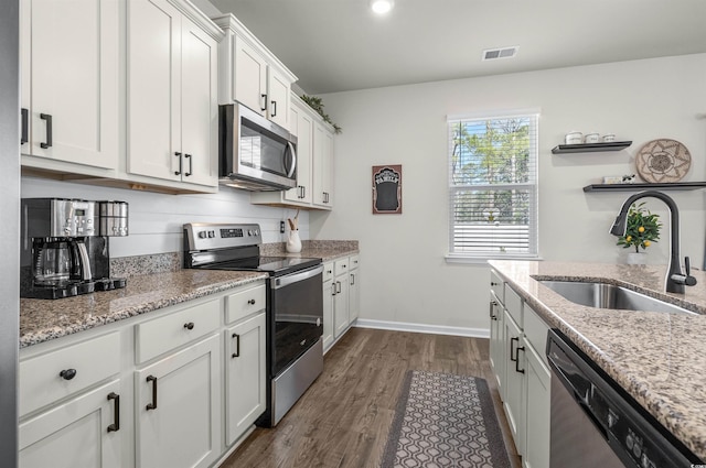 55 Porch Ln, Pawleys Island, SC 29585 - kitchen featuring stainless steel appliances, a sink, dark wood-style floors, white cabinetry, and light stone counters