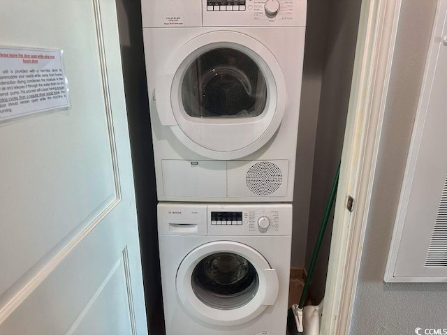 clothes washing area featuring stacked washing maching and dryer and laundry area