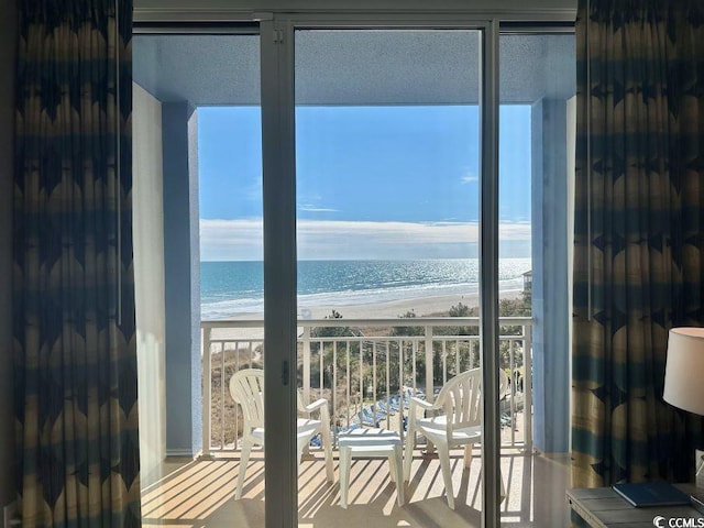 doorway to outside featuring floor to ceiling windows, a water view, and a beach view