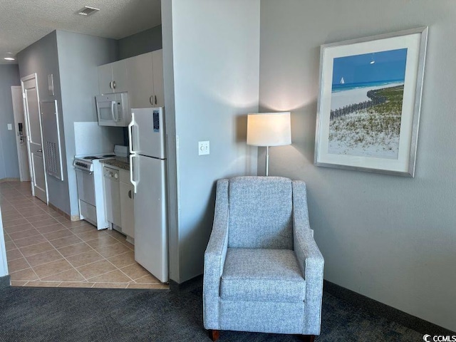 living area featuring light colored carpet, visible vents, a textured ceiling, and light tile patterned floors