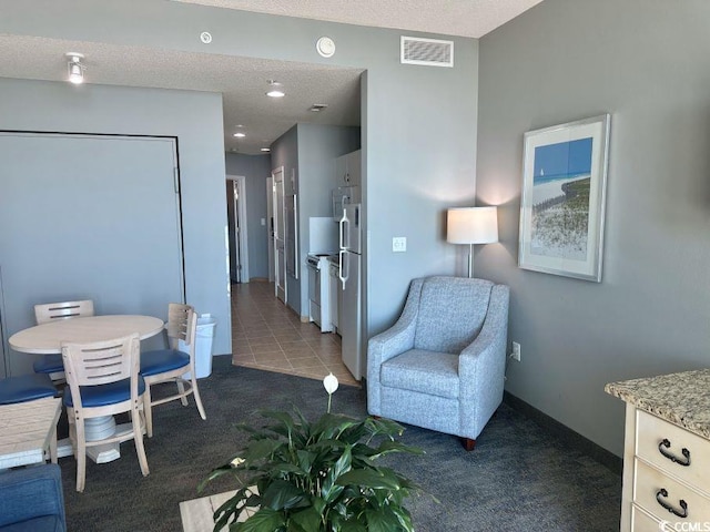 interior space with a textured ceiling, dark tile patterned floors, dark carpet, and visible vents