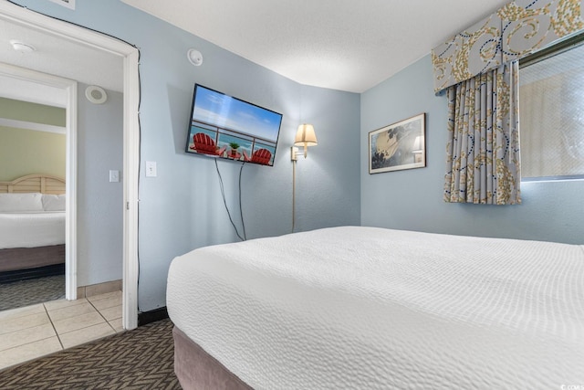 bedroom with tile patterned floors, baseboards, and a textured ceiling