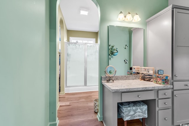 bathroom featuring baseboards, a shower stall, vanity, and wood finished floors