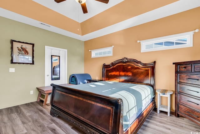 bedroom with ceiling fan, visible vents, and wood finished floors