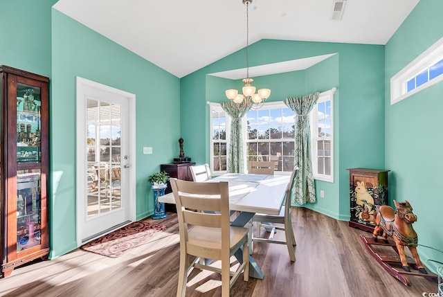 dining area with lofted ceiling, a notable chandelier, visible vents, and wood finished floors