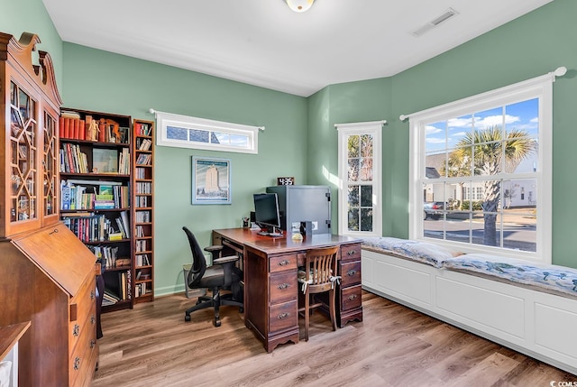 home office with light wood-style flooring and visible vents