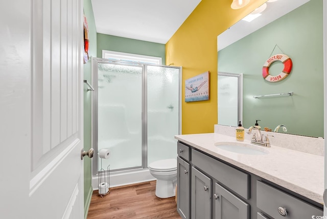 bathroom with toilet, a stall shower, wood finished floors, and vanity