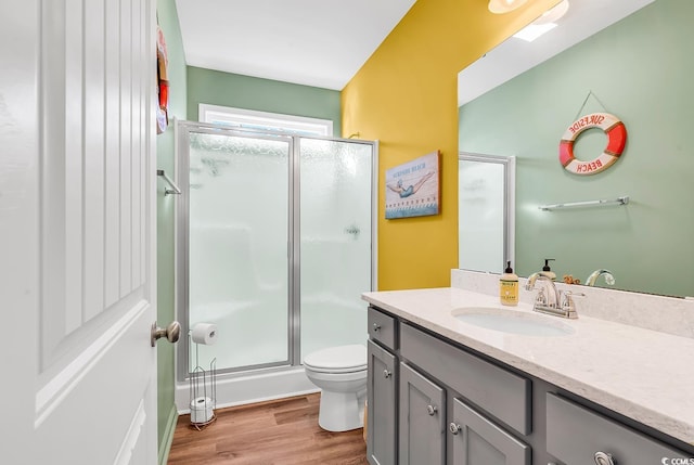 full bathroom with toilet, wood finished floors, vanity, and a shower with shower door