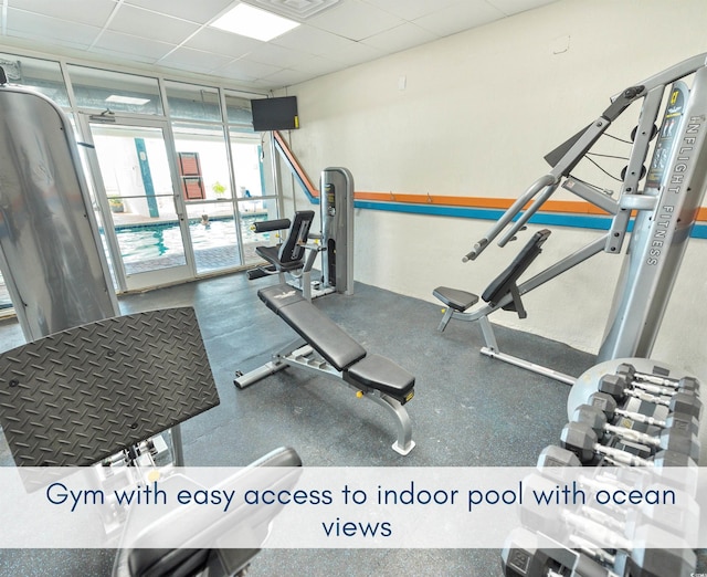 gym featuring a wall of windows and a drop ceiling