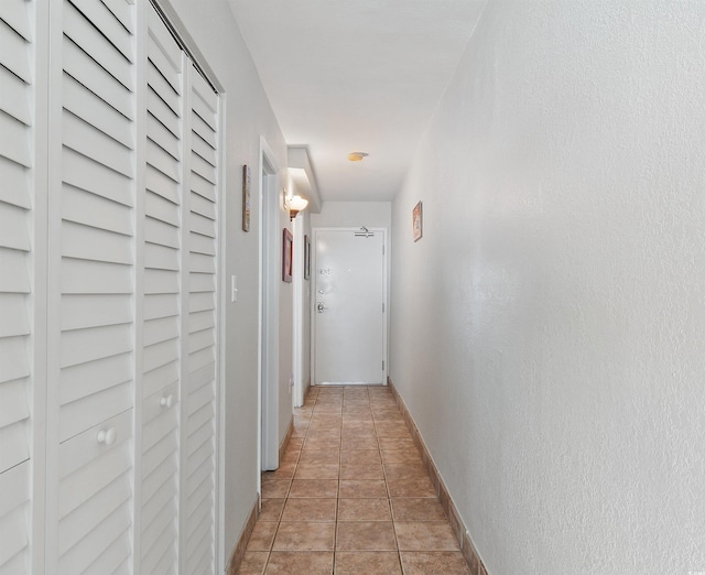 hallway featuring light tile patterned floors and baseboards