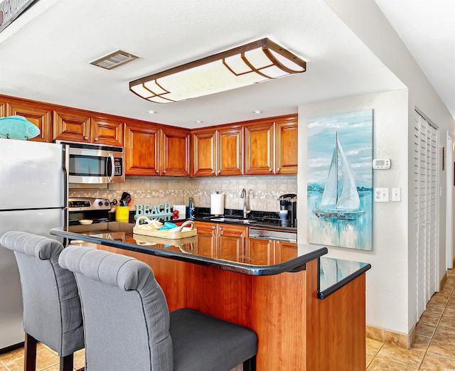 kitchen featuring light tile patterned floors, visible vents, decorative backsplash, stainless steel appliances, and a sink